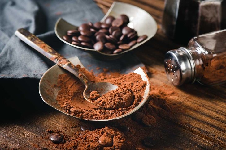 Cocoa powder and chocolate chip on wooden table.