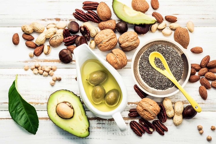 Selection food sources of omega 3 and unsaturated fats. Superfood high vitamin e and dietary fiber for healthy food. Almond ,pecan,hazelnuts,walnuts and olive oil on stone background.